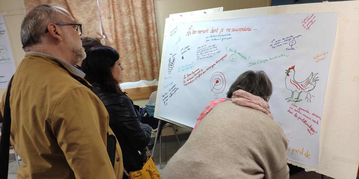 Participants à un atelier d'intellignec collective visuel qui dessinent leurs impressions sur une grande feuille avec des feutres de couleur